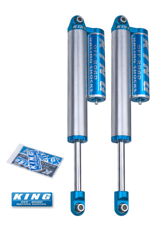 A set of King Shocks 00-10 Chevrolet Silverado 2500/3500 Rear 2.5 Dia Piggyback Reservoir Shocks, showcasing a blue and silver design with adjustable reservoirs to enhance ride quality. These shocks are designed for simple bolt-on installation and come with a decal packet and keychain featuring the King logo, making them an ideal choice for Chevrolet performance enthusiasts.