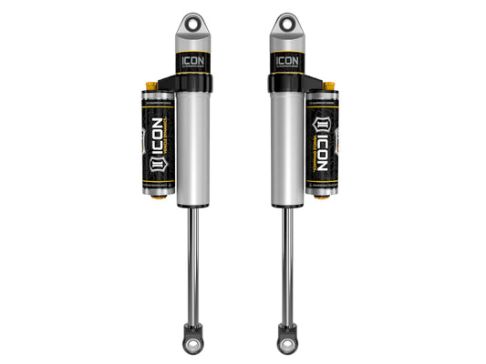 A pair of ICON's 01-19 GM HD 0-1in Rear / 2007+ GM 1500 4in Rear 2.5 Series Shocks VS PB CDCV, crafted in silver and black for superior off-road performance, equipped with cylindrical reservoirs at the top, featuring an adjustable valve for dynamic fine-tuning, and designed with a mounting eyelet at each end.