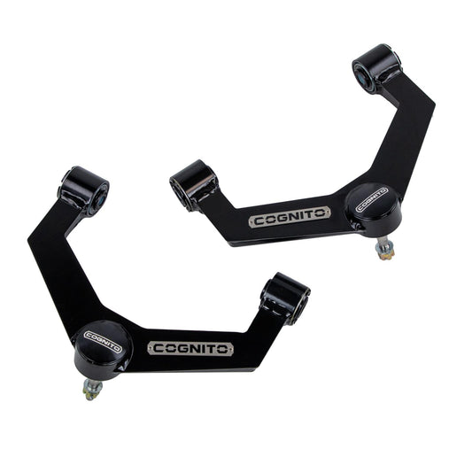 Two black mechanical parts with the brand name "Cognito Motorsports" prominently displayed. These suspension components, featuring precision uniball joints, are part of the Cognito Uniball SM Series Upper Control Arm Kit for 20-24 Silverado/Sierra 2500/3500 2WD/4WD, made of metal and designed for leveled and lifted applications. The parts are on a plain white background.