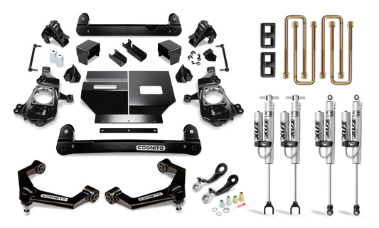 A variety of vehicle suspension and lift kit components, including parts for Silverado/Sierra 2500/3500 models from 2020 to 2024, are neatly arranged on a white background. The display features shock absorbers, control arms, brackets, bolts, and other metal parts. Many components are black or metallic and labeled "Cognito Motorsports," showcasing the Cognito 4-Inch Performance Lift Kit with Fox PS 2.0 IFP Shocks for both 2WD and 4WD configurations.
