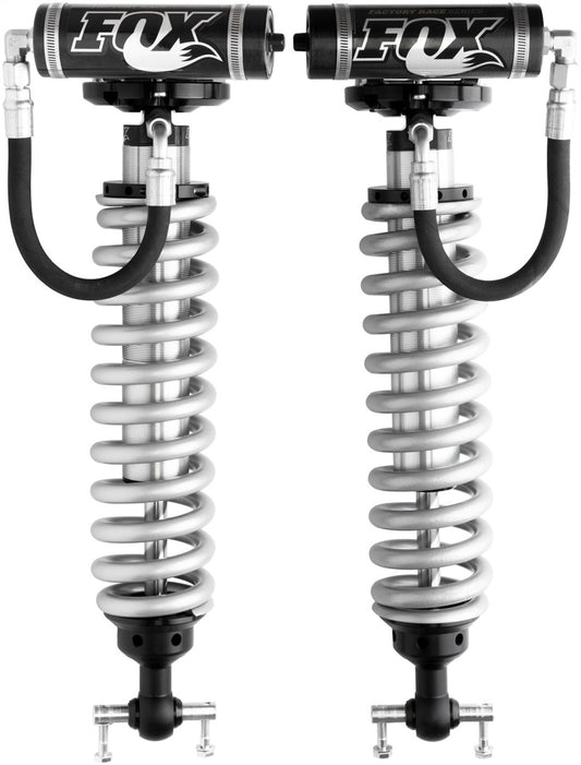 The Fox 2007+ Chevy 1500 Front 2.5 Factory Series Coilover Set for a 4-6.5 inch lift includes two silver shocks with black reservoirs and hoses, emblazoned with the "FOX" logo. These coilovers feature internal bypass technology, ideal for high-performance suspension systems to enhance off-road vehicle handling and comfort.