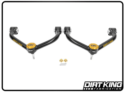 Two black DIRT KING control arms with gold accents, featuring Moog ball joints, are displayed side by side. Below are bolts, nuts, and a cotter pin. The "DIRT KING Fabrication" logo is at the bottom right. Product: 20-25 GM 2500/3500 Ball Joint Tube Upper Control Arms.