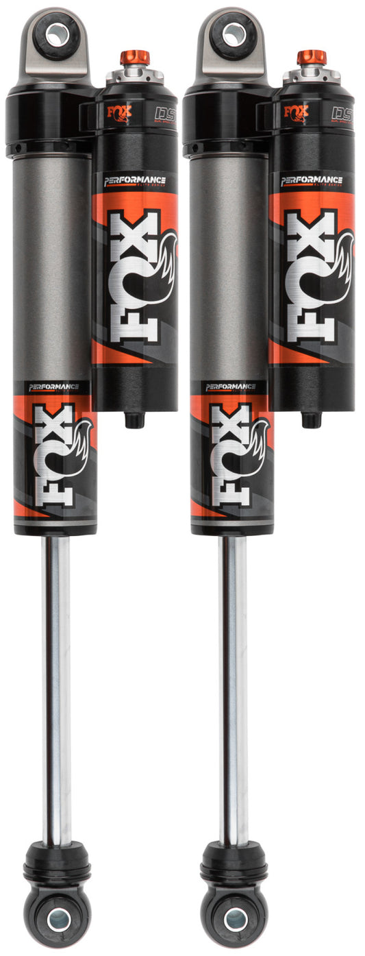 A pair of Fox Performance Elite Series 2.5 rear adjustable shocks for 20-Up GM 2500/3500 with a 0-1 inch lift, featuring FOX's signature colors and cylindrical design with visible rods at the bottom, and convenient top-mounted knobs for excellent adjustability.