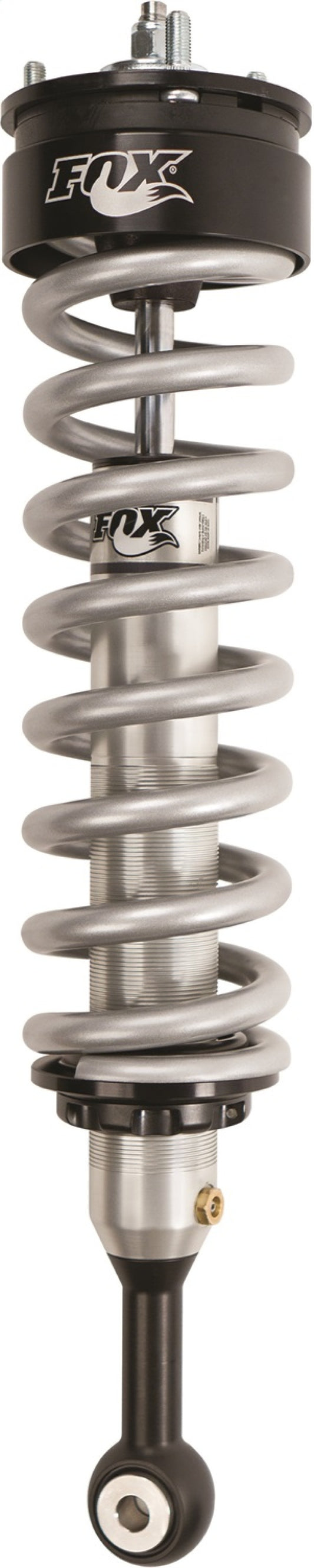 A close-up of a coiled suspension shock absorber showcases the Fox 14+ Chevy 1500 w/Factory Alum. UCA 2.0 Performance Series 4.1in. IFP Coilover Shock for a 0-2in. lift, featuring a silver spring and black mounts with aluminum bodies to enhance durability. Bearing the FOX logo at the top, it offers performance-focused shock valving optimized for off-road capabilities.