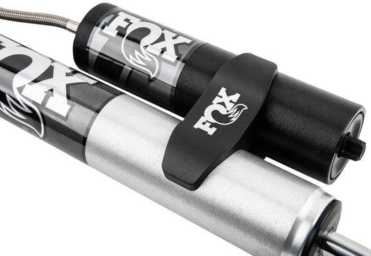 Close-up of the Fox 20-Up GM 2500/3500 HD Performance Series 2.0 Rear Smooth Body 1.5-3in Lift shock absorbers featuring a sleek black and silver design with the FOX logo prominently displayed. The image highlights performance-minded shock valving, high-performance engineering, and sturdy construction for impressive off-road capability.
