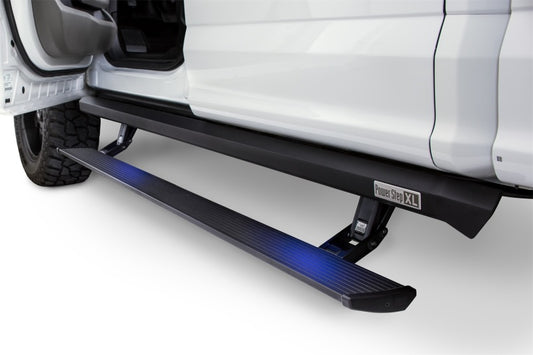 A close-up view showcases a white vehicle equipped with a black running board. The extended AMP Research PowerStep XL, ideal for Chevy Silverado 1500 Extended/Crew models from 2007-2013, features an electric-powered design with a blue illuminated light underneath. The vehicle door is open, revealing part of the tire.