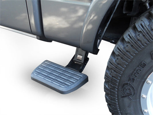 Close-up of a truck with the AMP Research 19-22 Chevrolet/GMC Silverado/Sierra 1500 Short Bed BedStep2 in black, displaying an extended side step and a large tire. The retractable step is positioned beneath the door for convenient access, while the tire highlights distinct tread patterns and a rugged design.