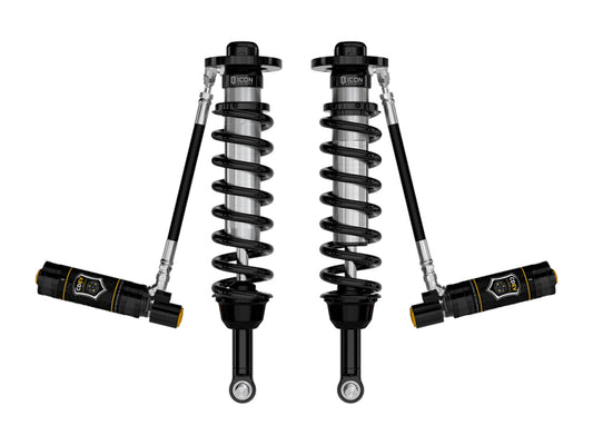 A pair of black coilover shocks with external reservoirs, crafted by ICON for the Ford F-150 Tremor suspension systems from 2021 to 2023, under the product name "ICON 21-23 Ford F150 Tremor 2.5-3in 2.5 Series VS RR CDEV Coilover Kit." These sleek, metallic components feature coiled springs and a connecting hose, epitomizing a robust and high-performance design.