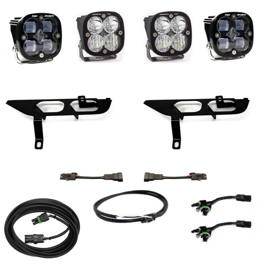 The Baja Designs 2021+ Ford F150 Fog Pocket Kit SAE Clear Squadron Sport DC with Upfitter by Baja Designs includes an off-road lighting setup featuring four square LED lights, two metal mounting brackets, and various wiring harnesses and connectors, all showcased on a white background.