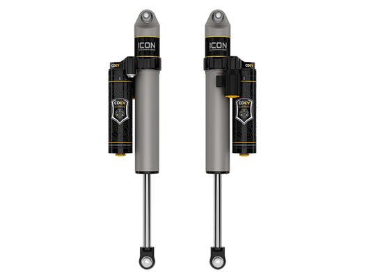 A pair of ICON 21-23 Ford F150 Tremor 4WD Rear 2.5 Series Shock VS PB CDEV are vertically aligned, showcasing a sleek silver and black design with yellow accents that highlight their modern and rugged appearance. These rebuildable shocks, featuring a compression damping valve, offer outstanding off-road performance for challenging terrains.