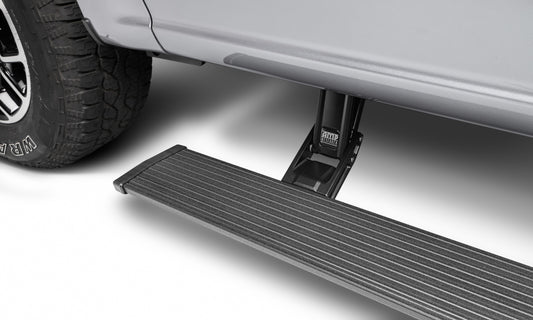 A close-up of the AMP Research 21-23 Ford F150 Hybrid/Lighting ONLY Power Step - Plug N Play reveals its textured surface for grip as it extends below the door. This electric-powered running board is mounted on a mechanism attached to the undercarriage, complementing the vehicle's metallic silver body and black tires.