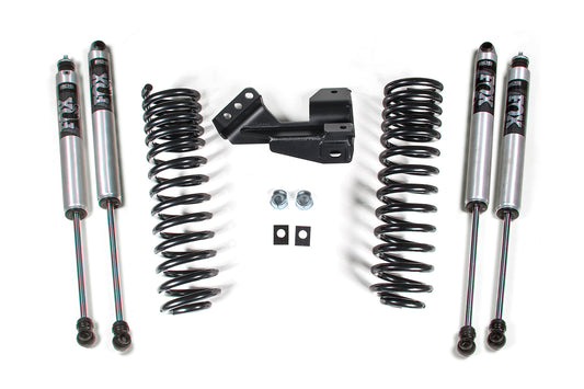 A set of automotive suspension components, including four silver Fox shock absorbers, two black Pro-Ride coil springs, a set of metal brackets, and bolts arranged symmetrically on a white background. This 2 Inch Leveling Kit | Performance Spring by BDS ensures optimal performance and style for Ford F250/F350 Super Duty (17-22) 4WD Diesel vehicles.