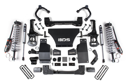 A selection of black and metallic automotive suspension parts, featuring coilover shocks, control arms, brackets, and a central plate showcasing the "BDS" logo, symmetrically displayed on a white background. Included in this collection are the FOX 2.5 Performance Elite Coil-Overs, specifically crafted for vehicles like the GMC Sierra 1500 or Chevy Silverado from model years 2019 to 2023 with diesel engines.