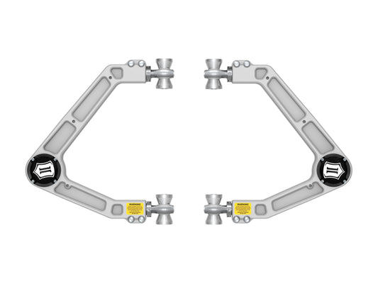 A pair of control arms, part of the ICON 2023+ Chevrolet Colorado Billet UCA DJ Pro Kit, exhibit a sophisticated design with gray metal accented by black and yellow details, featuring a triangular shape with rounded corners. These Delta Joint PRO components are tailored for off-road performance and are symmetrically arranged against a pristine white background.
