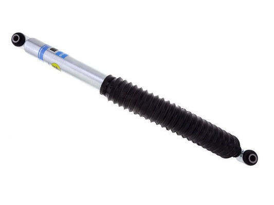 The Bilstein B8 5100 Series 07-18 GM 1500 Rear Shock Absorber from Bilstein Shocks is a silver automotive shock absorber designed specifically for lifted trucks and SUVs. It features a black protective boot and includes mounting holes at both ends for secure attachment in vehicle suspension systems.