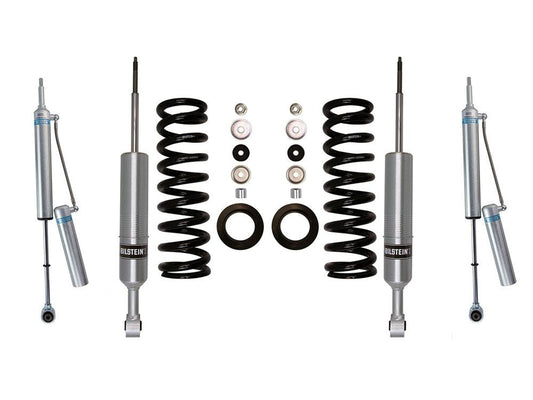 A suspension kit presented on a white background featuring four silver Bilstein shock absorbers, two black coil springs, and various black and silver mounting components is optimized for off-road capability. This LTW Motorsports 16-23 Toyota Tacoma 6 Lug Leveling Kit includes Bilstein 6112 Struts and Rear 5160 Shocks arranged symmetrically.