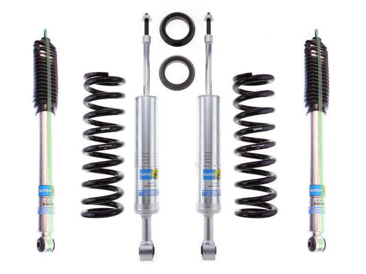 The image features the LTW Motorsports 05-15 Toyota Tacoma 6 Lug Leveling Kit, which includes four matching Bilstein 5100 rear shocks and two large coil springs. This set also comes with additional mounting components, with each silver shock absorber showcasing Bilstein's iconic blue and yellow branding.