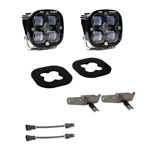 The Baja Designs 11-16 Ford Super Duty Squadron Pro Series Fog Pocket Kit features a pair of black LED lights with a four-lens design, perfect for your Ford Super Duty. The kit comes with two black mounting brackets, rubber gaskets, and wiring harnesses complete with connectors. The set is shown beautifully against a white background.