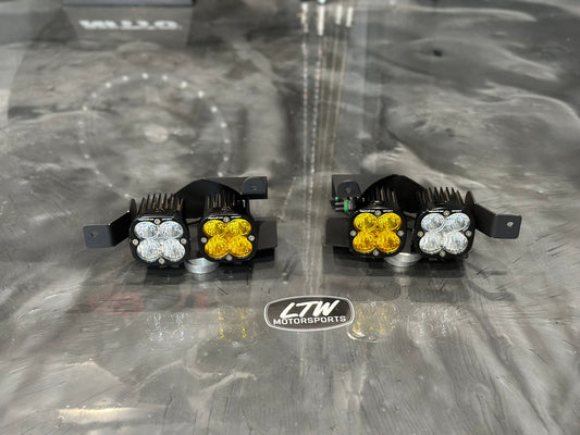 The 22-25 Chevy Silverado 1500 Fog Light Upgrade Kit by LTW Motorsports features two off-road LED lights with yellow and white lenses, curved heat sinks, and sturdy brackets. A logo reading "LTW Motorsports" is visible between the Chevy Silverado fog light brackets.
