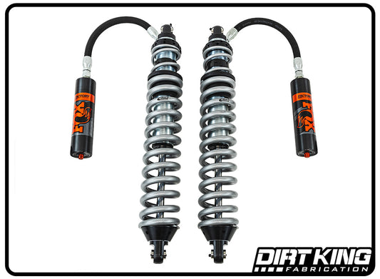 Image of two DIRT KING SHOCKS from the Dirt King 99-18 GM 1500 Long Travel Race Kit Spec Fox Coilovers, featuring remote reservoirs and surrounded by coiled springs. The shock absorbers and reservoirs are black with orange accents, epitomizing off-road performance. The Dirt King Fabrication logo is displayed at the bottom right corner of the image.