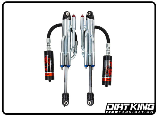 A pair of Dirt King 19-24 GM 1500 Long Travel Spec Fox Triple Bypasses off-road shock absorbers, featuring black, red, and silver detailing, displayed against a white background. The bypass shocks are connected to reservoirs via black hoses. Known for superior suspension dampening, the DIRT KING SHOCKS logo is shown in the bottom right corner.