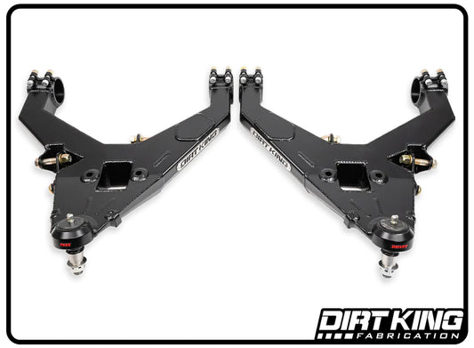 The image shows two black 19-24 GM 1500 Performance Lower Control Arms from DIRT KING, positioned symmetrically with their angled ends featuring heavy-duty Moog ball joints and bushings. Designed for off-road suspension systems, these control arms display the DIRT KING branding.